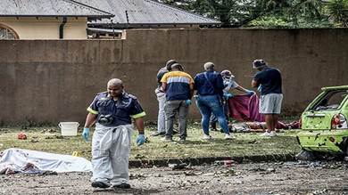 ضباط شرطة وخبراء الطب الشرعي خلال أداء عملهم في مدينة بوكسبورج شرقي جوهانسبرج، جنوب إفريقيا